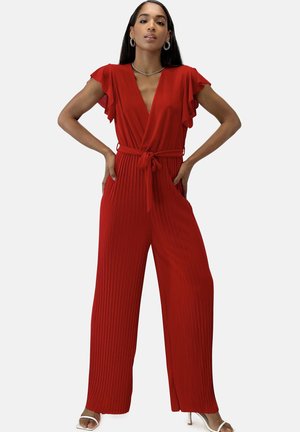 Rode geplooide jumpsuit met een diepe V-hals, vlindermouwen, een tailleband en zijzakken. De stof heeft een gladde, lichtgewicht textuur.