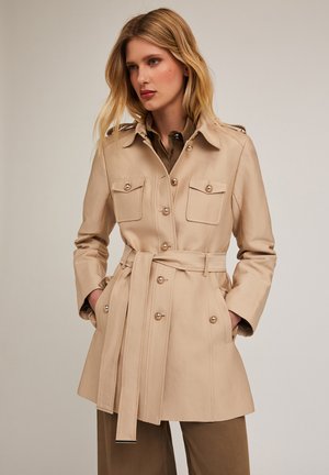 Cappotto trench beige con cintura realizzato in tessuto liscio, dotato di due tasche sul petto, bottoni in tono dorato e colletto regolabile.