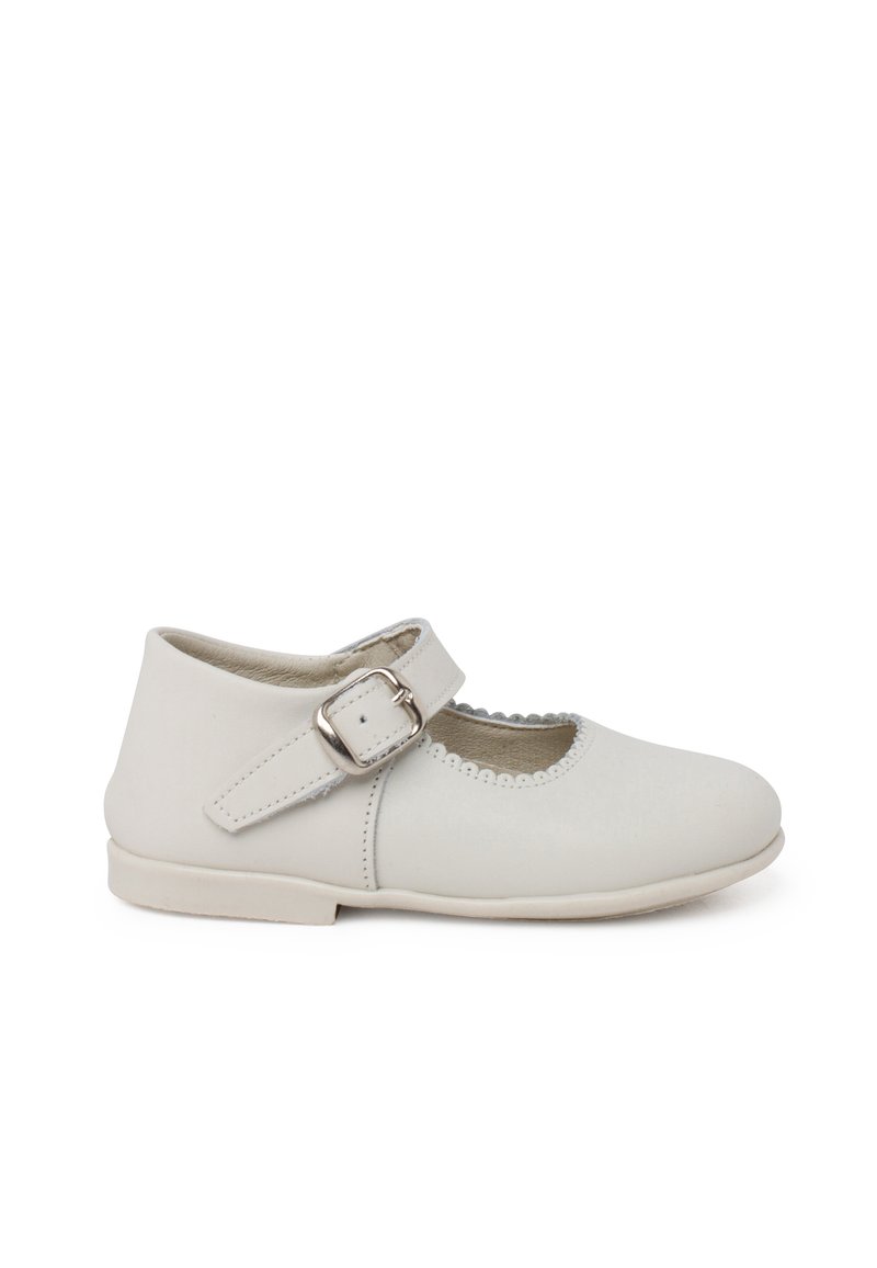 Zapato Mary Jane de cuero blanco con puntera redonda, correa ajustable con hebilla plateada y bordes festoneados. Suela plana.
