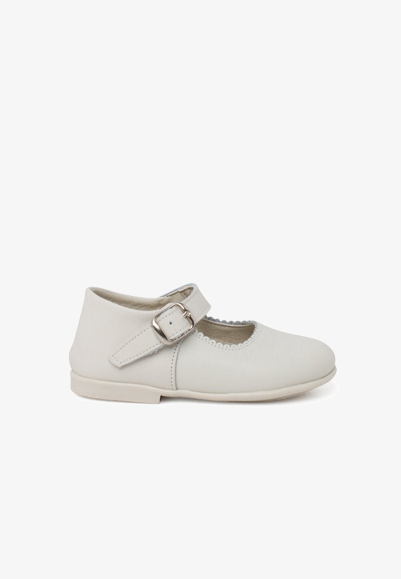 Zapato Mary Jane de cuero blanco con puntera redonda, correa ajustable con hebilla plateada y bordes festoneados. Suela plana.