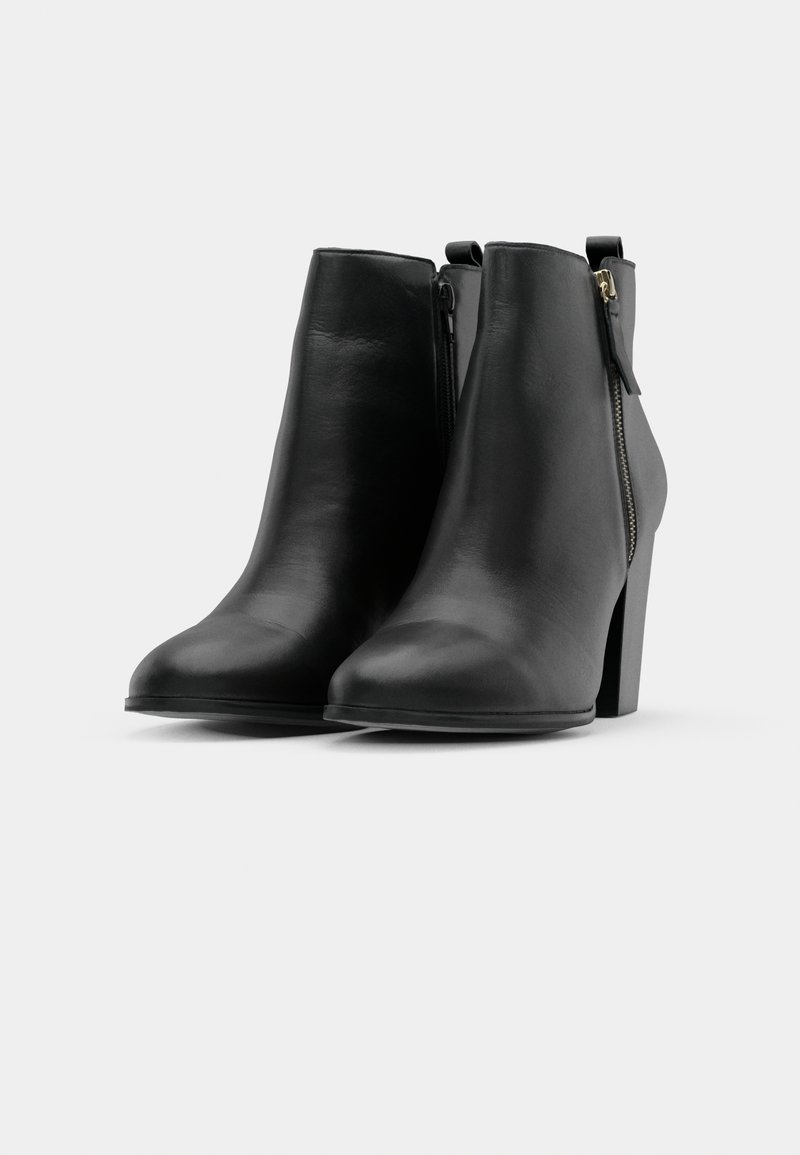 Schwarze Leder-Stiefeletten mit glatter Textur, runder Spitze und hohem Blockabsatz; verfügen über einen seitlichen Reißverschluss und eine Schlaufe für einfaches An- und Ausziehen.