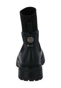 Botín negro de cuero con parte superior de textil negro acanalado. Presenta un acento metálico redondeado y una suela gruesa y texturizada.