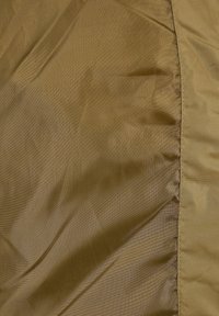 Tissu marron avec des coutures visibles et de subtiles plis, montrant une texture et différentes nuances allant du marron clair au marron foncé.