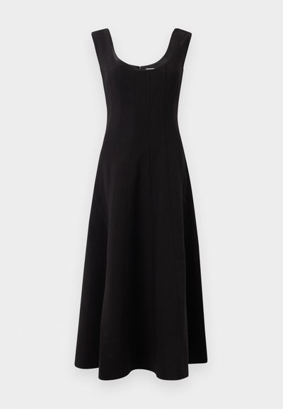 Melnā kleita ar apaļu izgriezumu, bez piedurknēm un izplūdušu A-klases siluetu. Satur vertikālas šuves, kas piešķir struktūru.