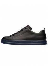 Black leather sneaker with rounded toe, flat lace-up design, and a thick navy rubber sole. Features subtle perforations and a heel tab.