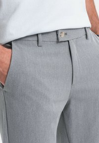 Harmaat housut tasaisella pinnalla, klassisella muotoilulla, suora leikkaus ja yksi nappisuljenta vyötäröllä.