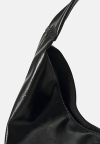 Sac à main en cuir noir avec une finition lisse et brillante ; présente une forme incurvée et une seule bandoulière avec un accent cousu.