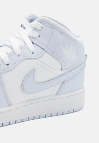 Svetlomodré a biele syntetické kožené tenisky s výrazným swoosh logom Nike, plochými bielymi šnúrkami, textúrovanou podrážkou a akcentom loga "Air Jordan".