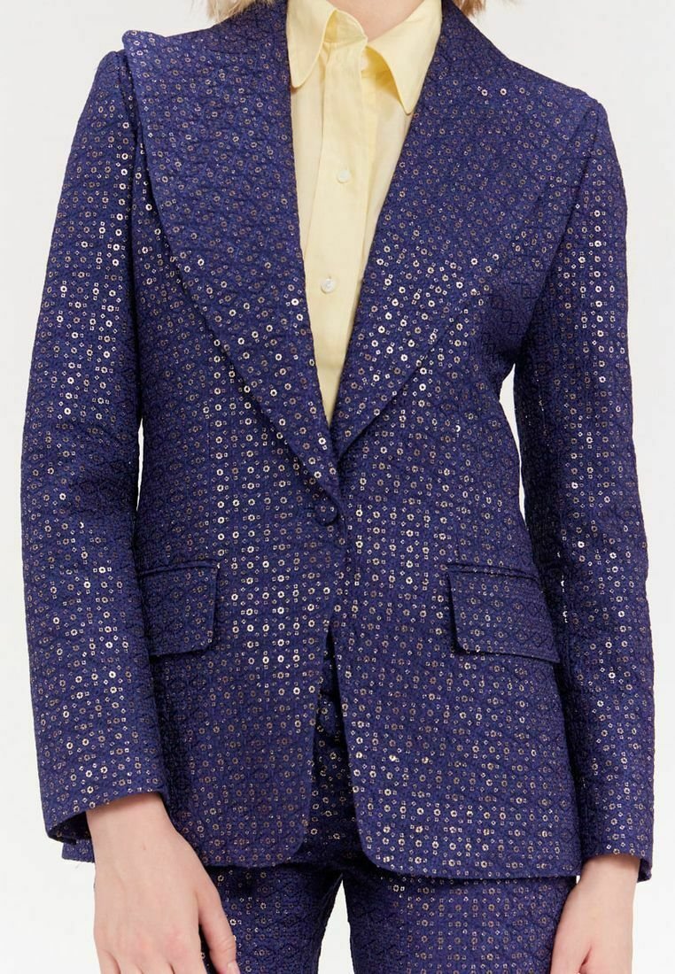 Blazer bleu marine avec un motif texturé mettant en avant des accents en anneau métallique, des revers larges, deux poches avant et associé à une chemise jaune.
