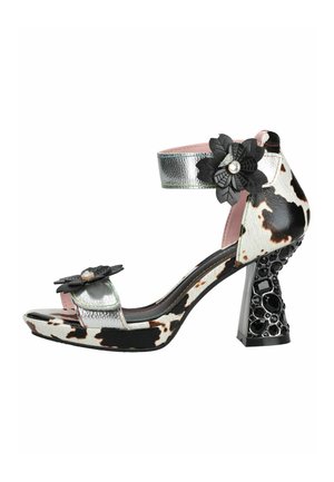 Sandalia de tacón alto para mujer con estampado de vaca en blanco y negro, tiras plateadas, decoraciones florales negras y tacón grueso con joyas.