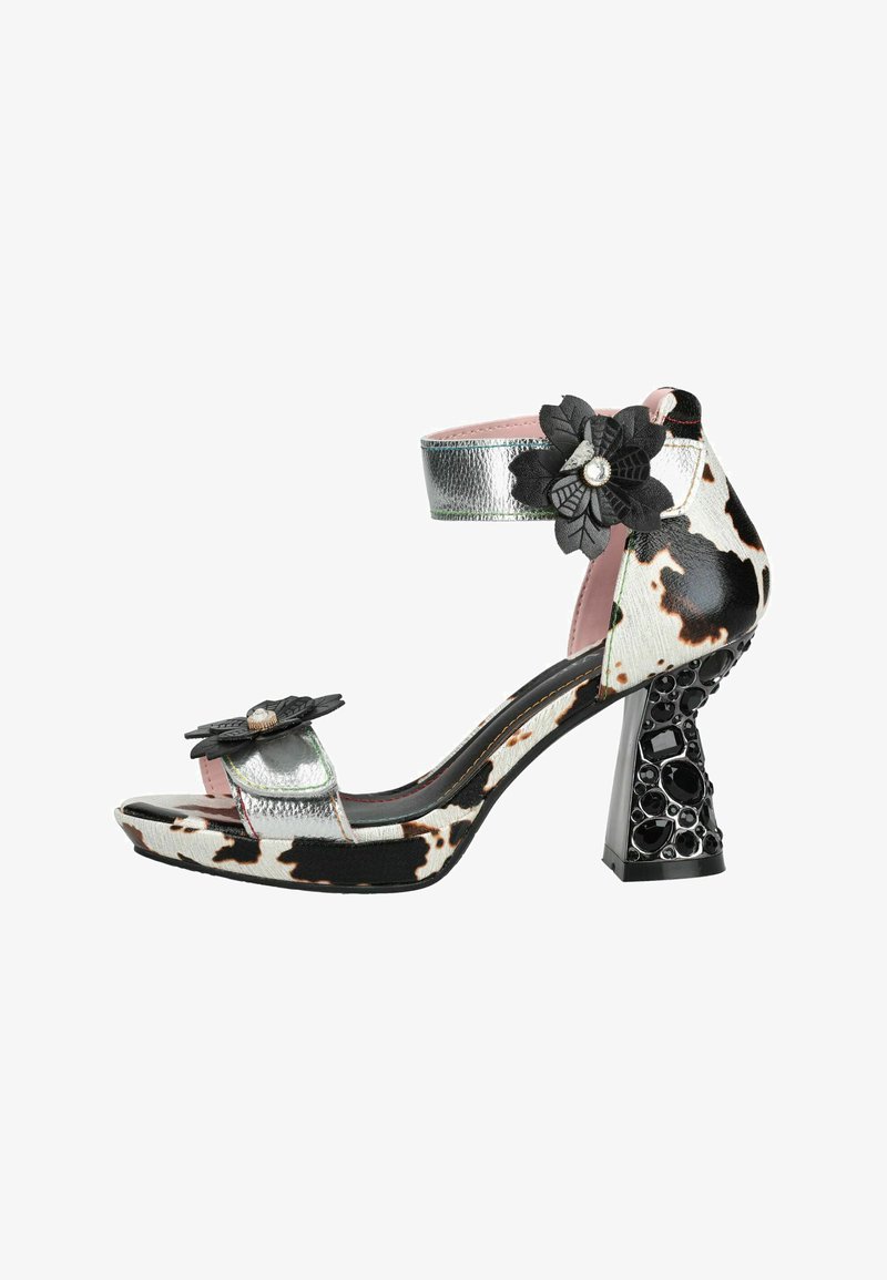 Sandale à talons hauts pour femme avec imprimé vache noir et blanc, brides argentées, décorations florales noires et talon bloc orné de bijoux.