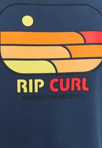 Granatowa koszulka z nadrukiem warstwowym w pomarańczowe, żółte i czerwone kształty, z napisem "RIP CURL" w wyrazistych kolorach poniżej.