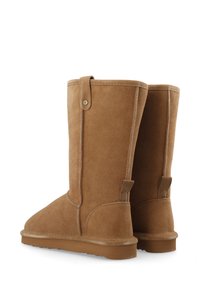 Ein Paar tanfarbene Wildlederstiefel bis zur Wade mit flachen braunen Sohlen, vertikalen Nähten und Zuglaschen hinten und an der oberen Seite.