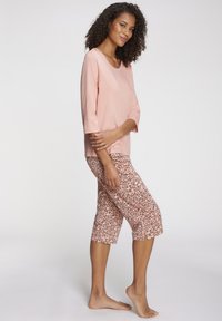 Light pink, long-sleeve top paired with leopard print capri pants in soft fabric. Rounded neckline and relaxed fit with mid-calf length.