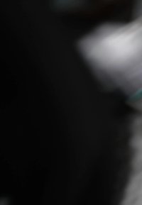 Crna i siva zamućena pozadina s naznakama bijelih i tirkiznih detalja. Glatka tekstura s blagim svjetlosnim efektima. Nejasni oblici su vidljivi.