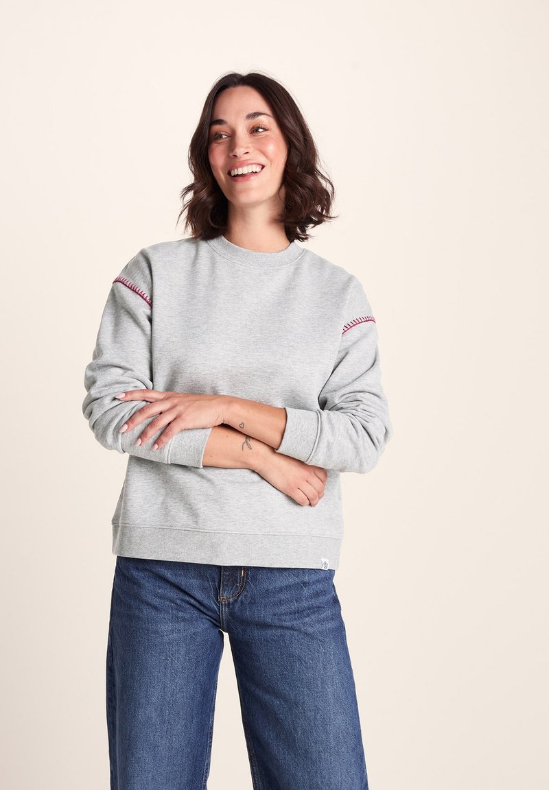 Gray sweatshirt with round neckline and red stitching accents on sleeves. Pair of blue wide-leg jeans completes the outfit. Smooth texture.