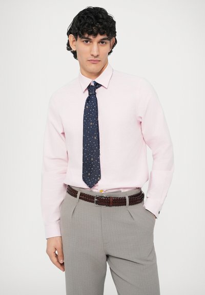 Cămașă roz deschis cu guler, cravată bleumarin cu modele mici, pantaloni gri cu o curea maro împletită, croială slim fit, textură netedă.