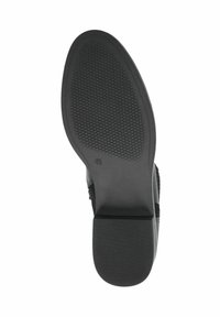 Semelle de chaussure noire avec une surface en caoutchouc texturée, présentant un motif de semelle pour une meilleure adhérence et une zone de talon renforcée.