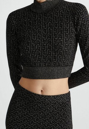 Schwarzes, kurzes Sweatshirt- und Rockset mit silbernem geometrischem Muster, das den Bauch und lange Ärmel zeigt.