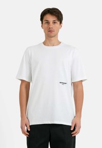 T-shirt bianca in cotone con maniche corte, colletto rotondo e piccolo logo nero "SIXTHJUNE PARIS" stampato sul lato sinistro. Tessuto liscio.