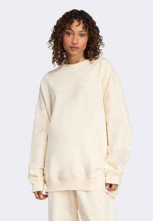Sweatshirt oversize crème en tissu doux, avec un col rond côtelé, des manches longues à poignet et un logo Adidas ton sur ton sur le devant.