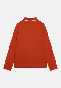 Polo tričko s dlouhým rukávem v živé oranžové barvě, s klasickým límečkem s bílými detaily. Hladká, texturovaná látka, rovný spodní lem.