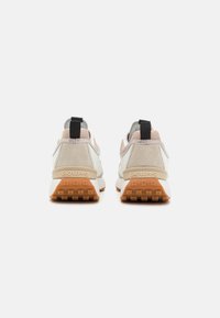 Bílé a šedé sportovní boty s béžovými semišovými doplňky, s texturovaným zadním dílem, zadním poutkem a gumovou podrážkou s protiskluzovými vzory.