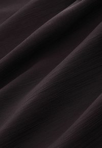 Sötét anyag finom textúrával, amely puha, sima redőkkel és mély szénszürke színben pompázik.