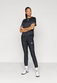 Black athletic set featuring a short-sleeve top with white accents and fitted pants, made from smooth, lightweight fabric.