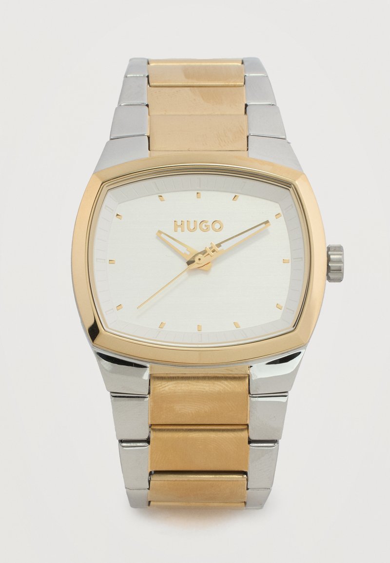 Ανδρικό ρολόι Hugo με ορθογώνιο μπράτσο από ανοξείδωτο ατσάλι σε χρυσό και ασημί και λευκό καντράν με χρυσά δείκτες και σημάδια.
