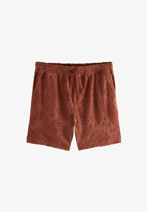 Rust-colored swim shorts made of textured fabric, featuring a raised floral pattern, elastic waistband, and drawstring closure.
