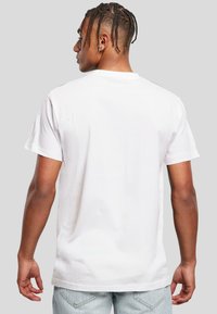 White cotton t-shirt with short sleeves, simple design, crew neck, smooth texture, and straight fit, worn with light blue denim jeans.
