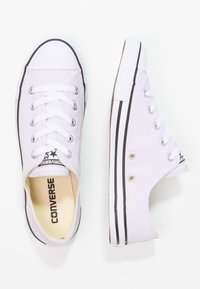 Vita canvas sneakers med svarta detaljer, rund tå och vita snören. Har metallöglor och en strukturerad gummisula.