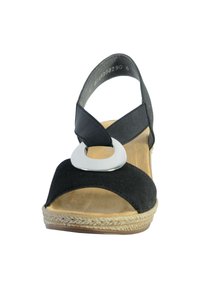 Sandalo in suede nero con una larga fascia, accentuazione circolare in argento e una soletta texturizzata di colore naturale, con suola in juta intrecciata.