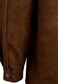 Bruine suède kleding met een gladde textuur, zichtbare stiksel en een knoopmanchet detail. De stof lijkt zacht en duurzaam.