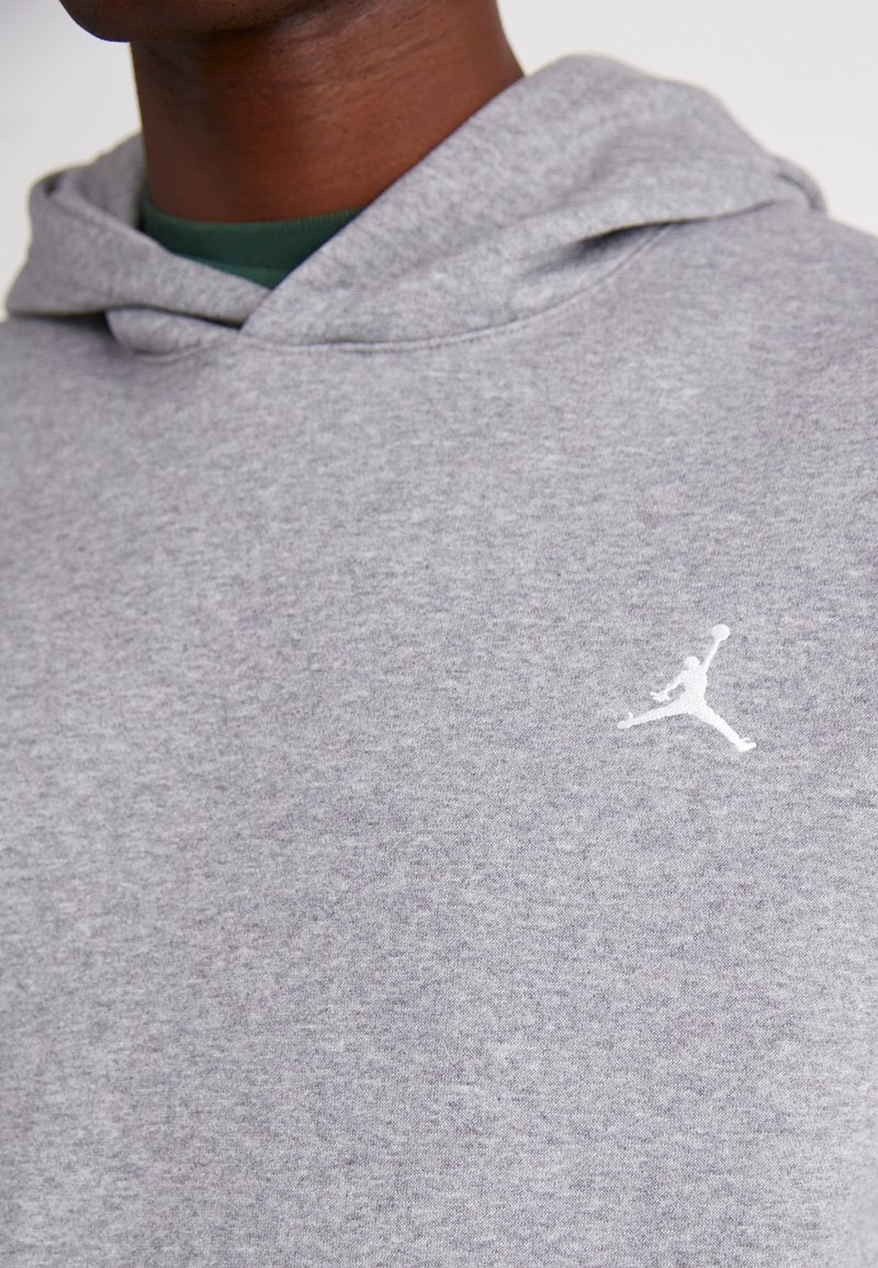 Grauer Baumwoll-Hoodie mit strukturierter Oberfläche, featuring ein weißes Jordan-Logo auf der Brust und einer Kordelzugkapuze.