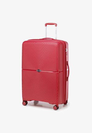 Valigia rigida rossa con texture a cerchi concentrici, manico retrattile e quattro ruote per la mobilità. Presenta un logo di marca.