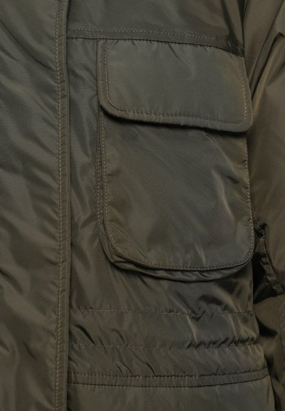 Dark green jacket pocket with a flap closure, detailed stitching, and padded fabric texture, shown in close-up.