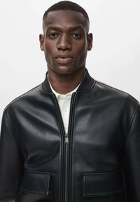 Chaqueta bomber de cuero negro con cremallera frontal, cuello acanalado y dos bolsillos frontales. Textura suave, diseño ajustado, estilo minimalista.