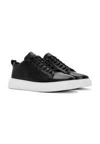 Sneakers neri in pelle con finitura liscia, punta arrotondata, suola in gomma bianca e lacci tono su tono; presentano un piccolo tallone per facilitare l'indossamento.
