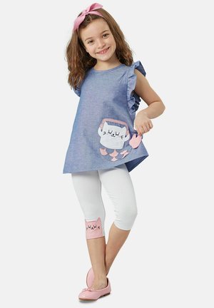 Denim-tunika med volangärmar, med en kattficka, kombinerad med vita leggings med rosa kattdetaljer och rosa ballerina-skor.