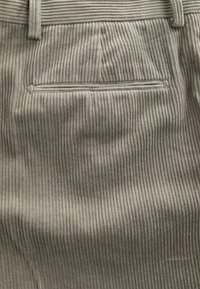 Gray corduroy pants featuring vertical ribbing, a back pocket with a rounded edge, and a subtle texture throughout the fabric.