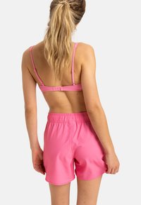 Roze tweedelige zwemoutfit met een aangesloten top met verstelbare banden en bijpassende shorts met elastische tailleband. Glad, lichtgewicht stof.