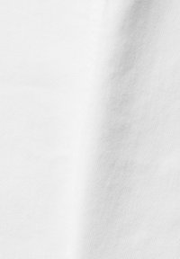 Tissu blanc uni avec une texture de tissage visible et de légers plis créant des ombres douces.