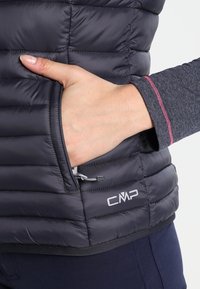 Dunkelblaue Steppweste aus gestepptem Material, mit seitlichem Reißverschlussfach, CMP-Logo am Saum und kontrastierendem Stichdetail.