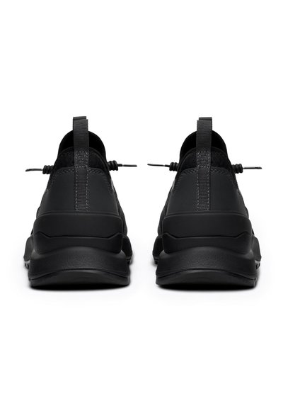 Crne sportske cipele s glatkom teksturom gornjeg dijela, izdržljivom potplatom i elastičnim vezicama. Peta ima trakicu za lakše obuvanje.