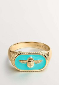 Anillo de oro con un centro ovalado de esmalte turquesa que presenta un diseño en relieve de un escarabajo. Un borde texturizado rodea el esmalte. Marcado "aristocrazy".