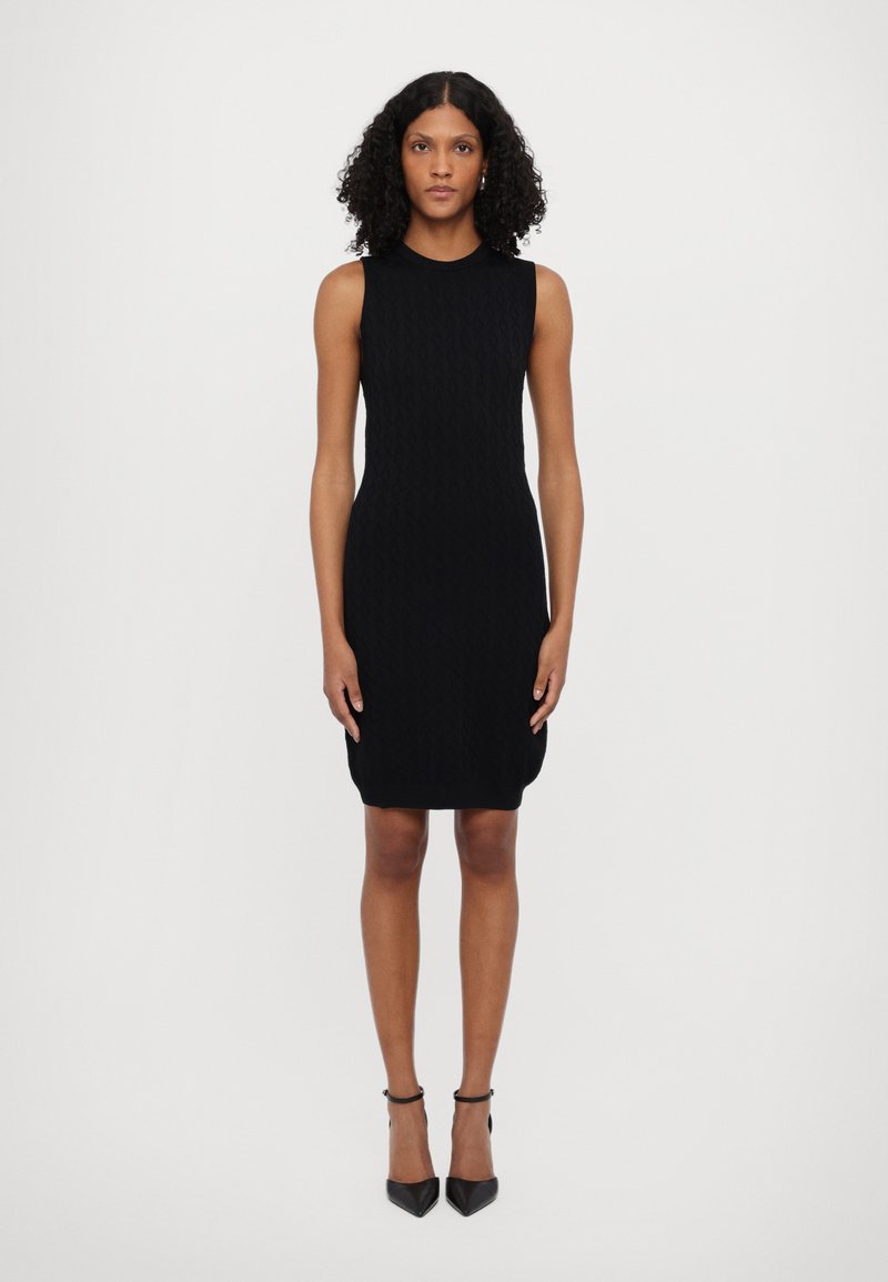 Crna pletena haljina bez rukava s dizajnom koji se prilagođava figuri, s teksturiranim uzorkom i rubom koji pada iznad koljena.