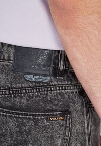Mustat farkut sisältävät tekstuuripatchin, jossa on kohokuvioitu grafiikka ja etiketti, joka kertoo veden säästämisestä. Herkkä kultainen "Volcom" -korostus taskussa.