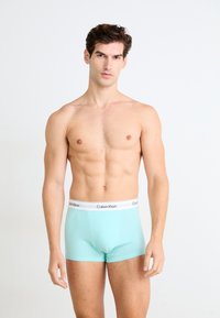 Lichtblauwe Calvin Klein boxershort met een witte elastische tailleband waarop de merknaam in het zwart is gedrukt, aansluitend en glad materiaal.